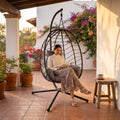 Silla colgante en terraza con una mujer leyendo